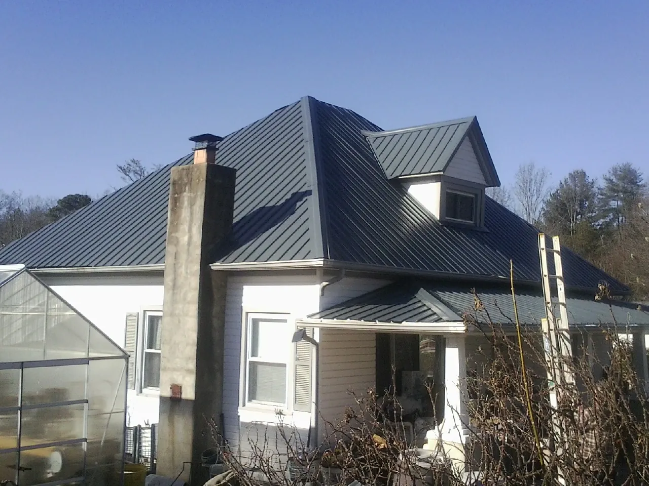 Dark blue standing seam metal roof on a white farmhouse with dormer — Slate & Tile Roof Repair by Roofing Brothers in Angels Camp