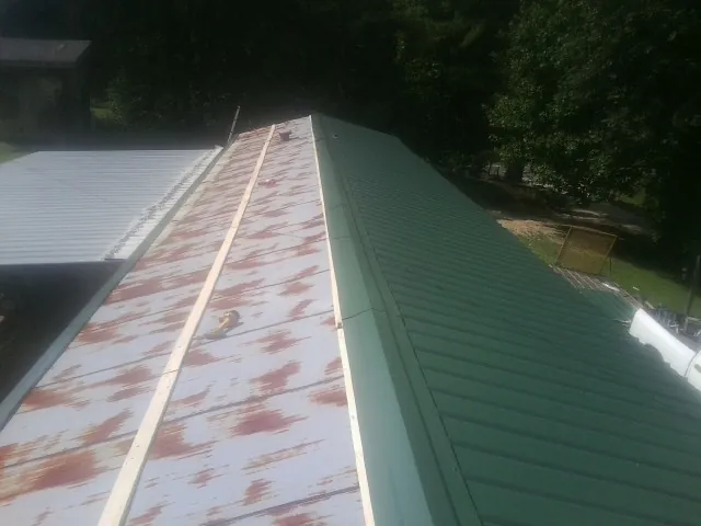 Old rusted panels beside newly installed green metal roofing — Wind Damage Roof Repair by Roofing Brothers in Angels Camp