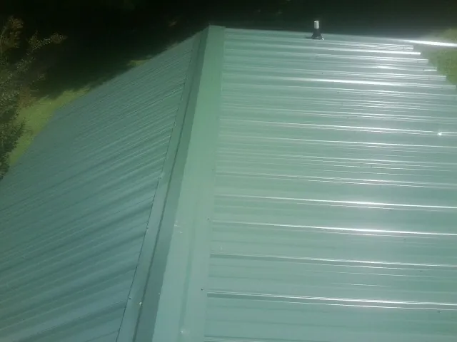 New green metal panels meeting at the ridge of a roof — Flat Roof Repair work by our crew in Angels Camp