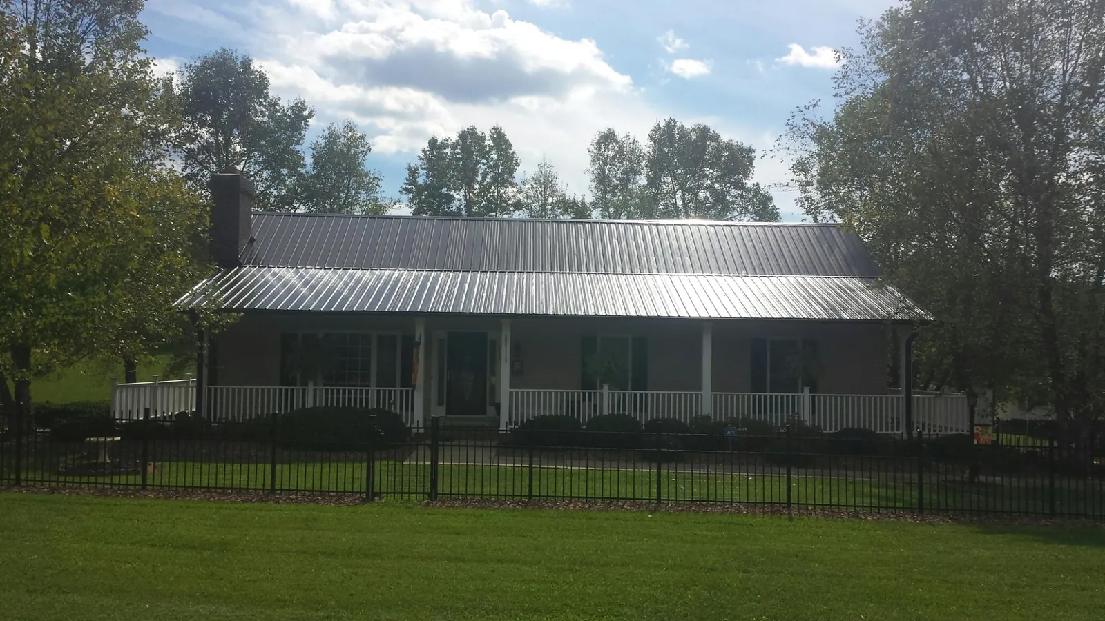 Gray metal roof on a brick ranch with a full width front porch — Gutter Guard Installation work by our crew in Angels Camp