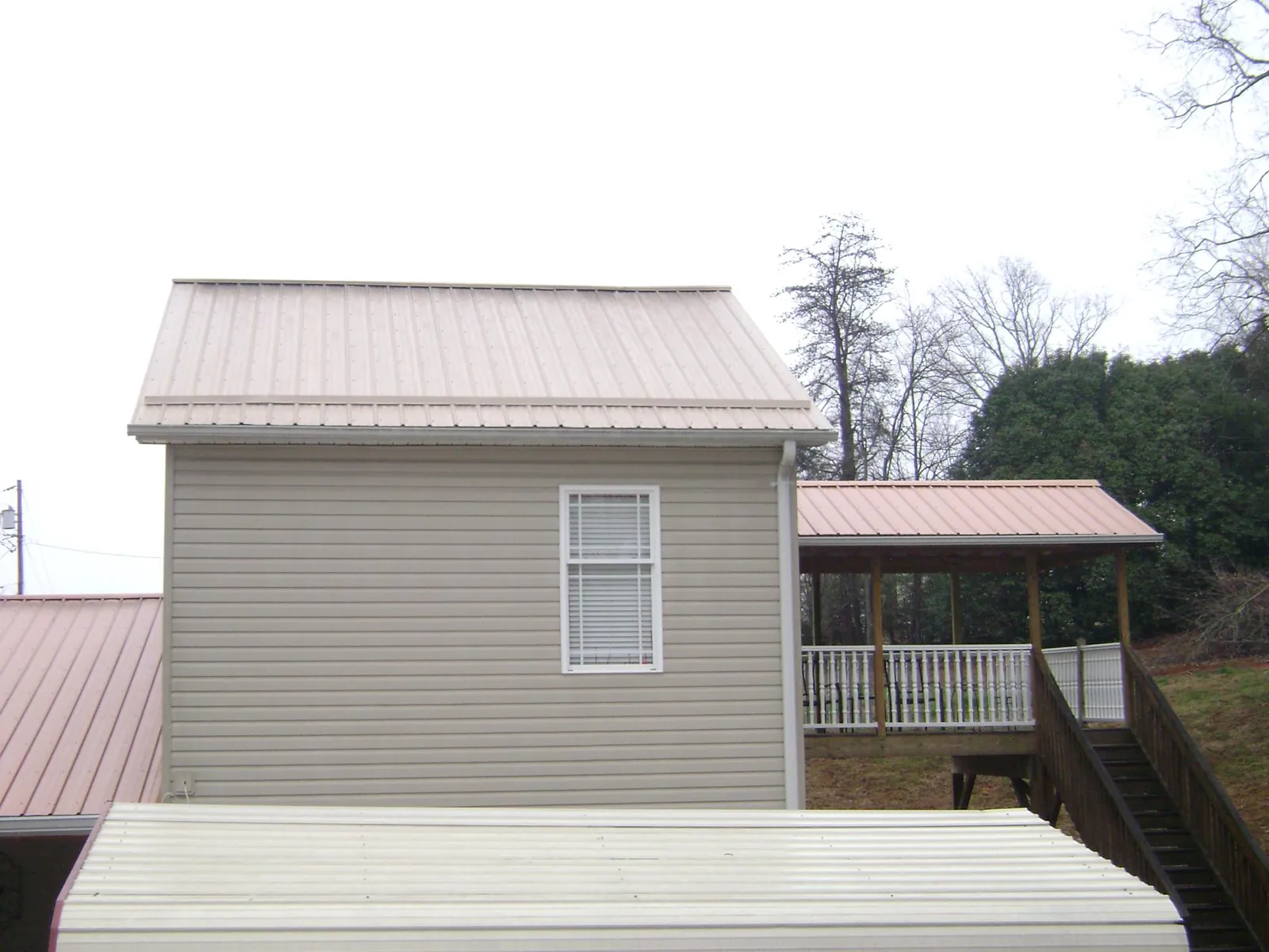 Tan metal roofs on a two story addition and attached porch, from a Roof Replacement job in Angels Camp