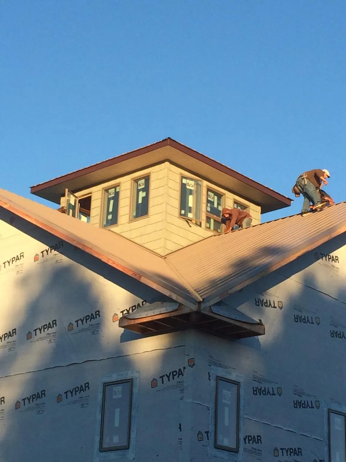 Roofers working around a rooftop cupola on a new metal roof at sunset — Roof Waterproofing in Angels Camp by Roofing Brothers